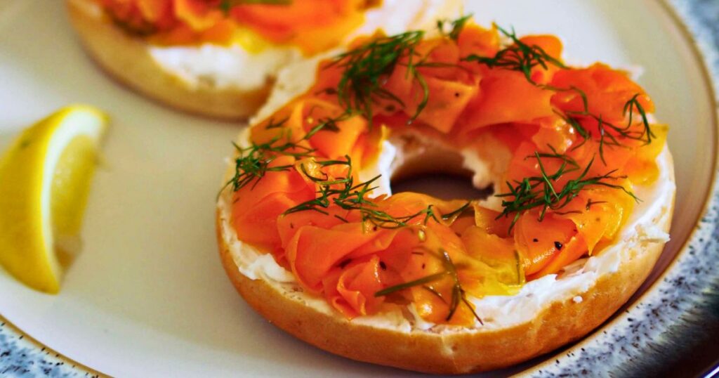 A plant-based smoked salmon bagel topped with cream cheese, capers, and fresh herbs.