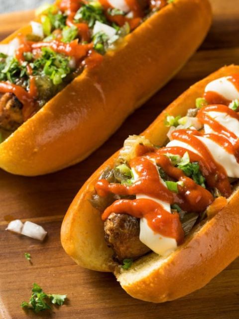 Plant-based sausages topped with condiments and served in a bun.