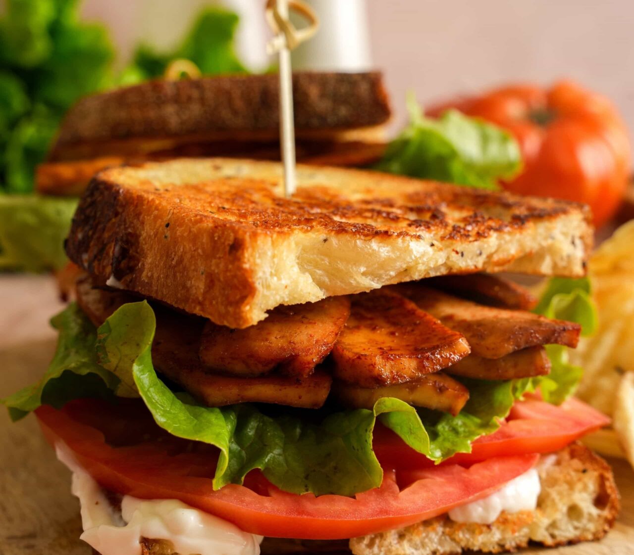 Crispy tofu BLT stacked with smoky tofu bacon, butter crunch lettuce, sliced tomato, and vegan mayo on golden toasted bread.