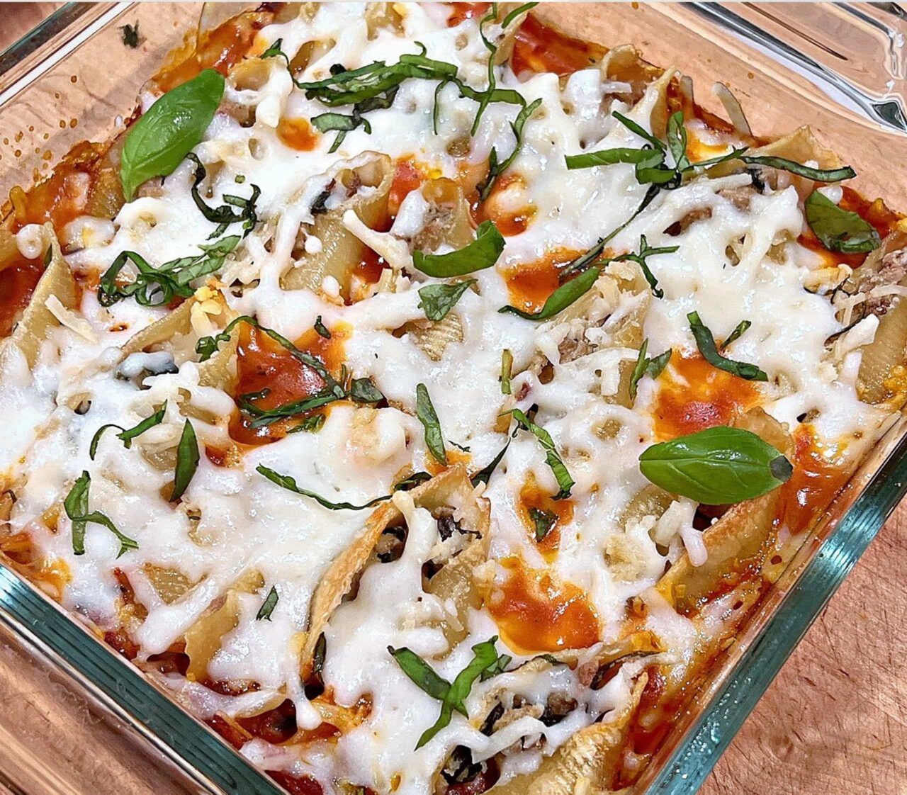 Garlic and Herb Stuffed Shells in a square glass baking dish with melted dairy-free mozzarella, marinara sauce, and fresh basil.