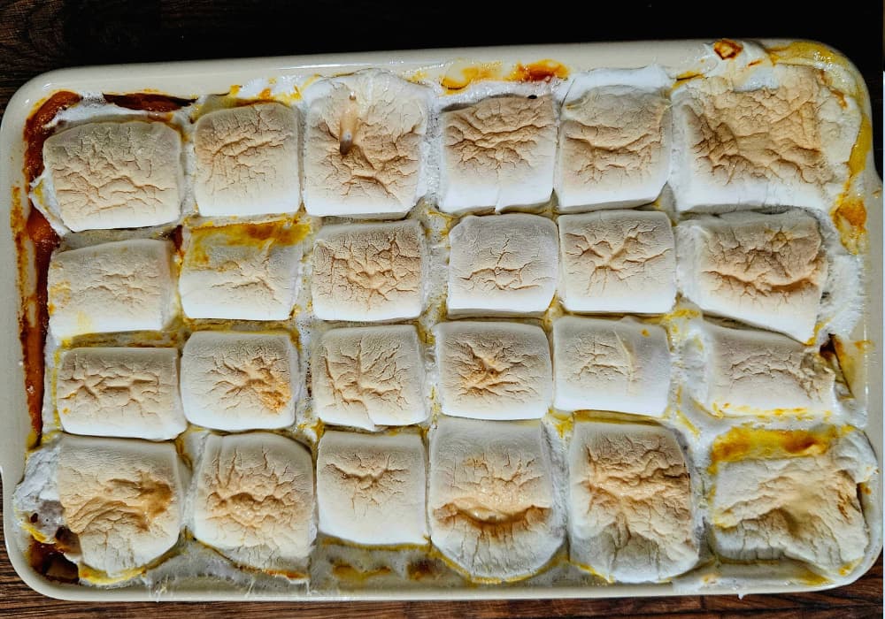 Overhead view of Sweet Potato Casserole with Marshmallows in a baking dish, topped with rows of golden, toasted marshmallows.