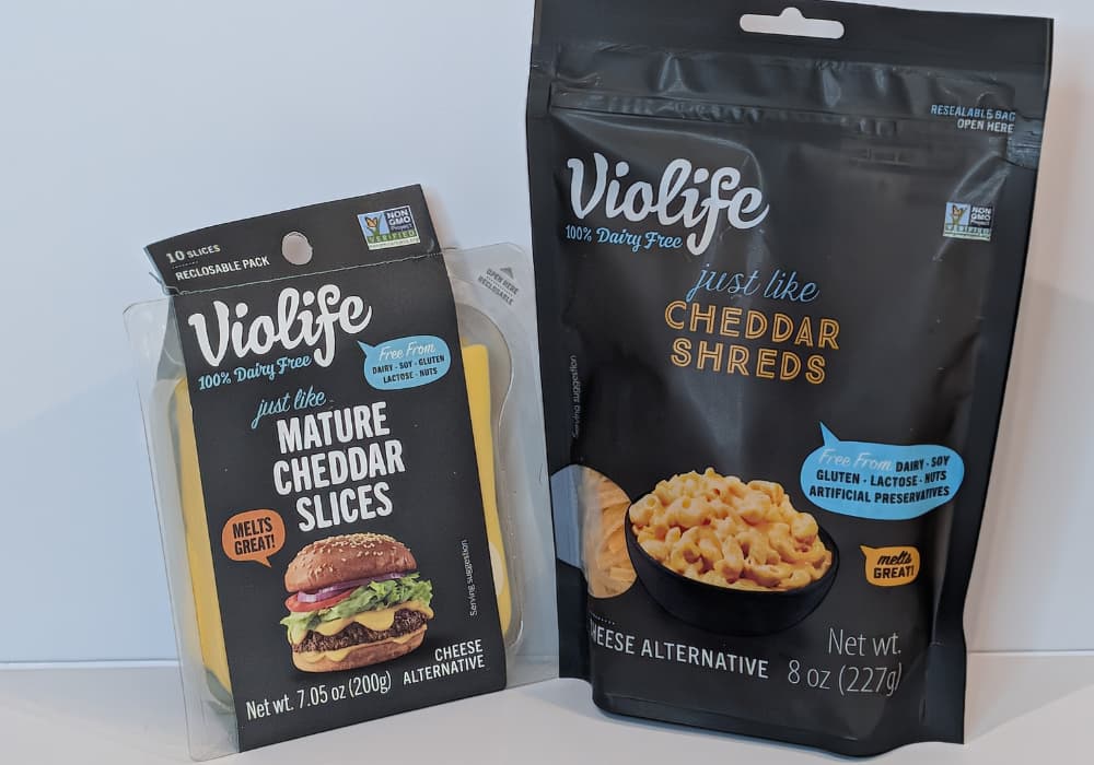 Violife dairy-free cheddar in two formats, mature cheddar slices and cheddar shreds, on a white background.